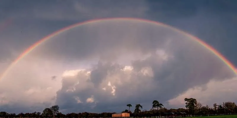 Farm field with rainbow and dark clouds